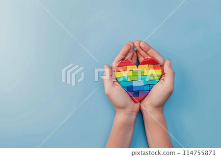 hands holding a rainbow heart on a blue background 114755871