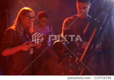 Video production crew working together backstage on set in red neon lights, copy space Video production crew working together backstage on set in red neon lights, copy space 114758788