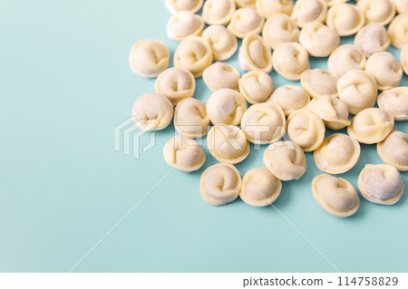 Semi-finished raw dumplings lie on a blue background, copy space. 114758829