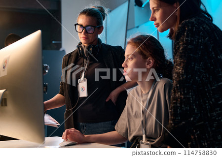 Side view portrait of three female creators looking at computer screen together in studio copy space 114758830