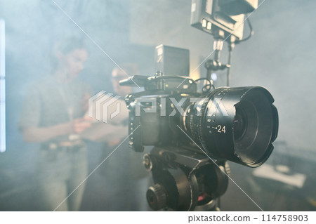 Background image of professional digital video camera on stand in video production studio with smoke effect copy space Background image of professional digital video camera on stand in video production studio with smoke effect copy space 114758903