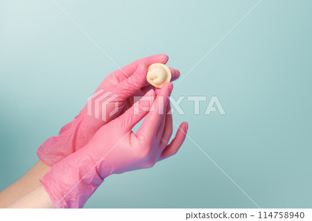 Close-up of a female chef's hands in rubber gloves holding a raw dumpling, concept for the neat production of semi-finished food, copy space. 114758940