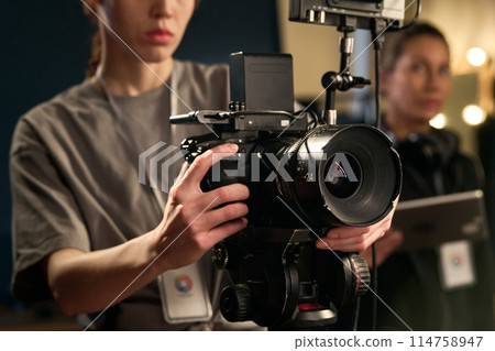 Close up of female hands holding professional video camera and operating equipment on set copy space 114758947