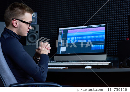 Thoughtful sound engineer focusing on track while working on computer in studio Thoughtful sound engineer focusing on track while working on computer in studio 114759126