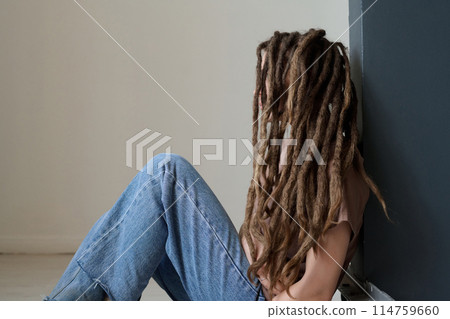 Side view portrait of unrecognizable woman with long dreadlocks sitting on floor minimal copy space 114759660