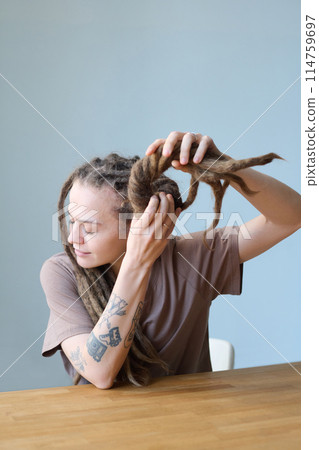 Vertical portrait of young woman with dreadlocks trying bun hairstyle in minimal setting, copy space Vertical portrait of young woman with dreadlocks trying bun hairstyle in minimal setting, copy space 114759697