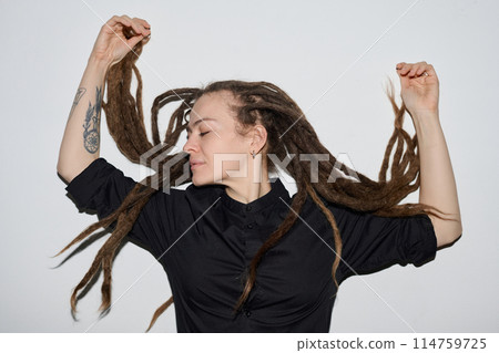 Minimal portrait of Caucasian woman with long dreadlocks dancing on white background shot with flash 114759725