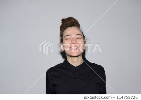 Minimal portrait of Caucasian woman with dreadlocks in bun hairstyle and candid big smile standing on white background shot with flash copy space 114759726