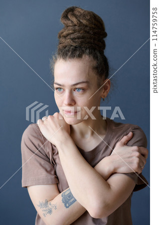 Candid portrait of smiling Caucasian woman with dreadlocks in bun hairstyle and no makeup looking away on grey background Candid portrait of smiling Caucasian woman with dreadlocks in bun hairstyle and no makeup looking away on grey background 114759758