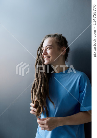 Vertical side view portrait of smiling Caucasian woman with long dreadlocks hairstyle looking away 114759770