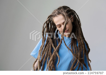 Minimal waist up portrait of Caucasian young woman with long dreadlocks standing on white with eyes closed copy space Minimal waist up portrait of Caucasian young woman with long dreadlocks standing on white with eyes closed copy space 114759787