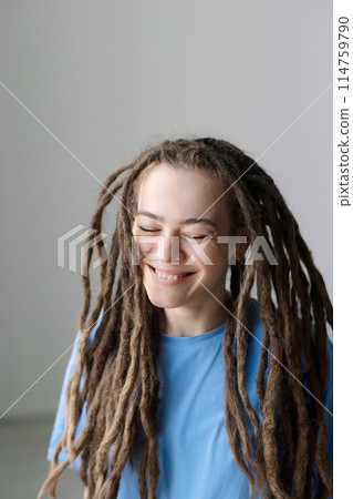 Minimal portrait of carefree Caucasian woman with long dreadlocks hairstyle and eyes closed smiling on white 114759790