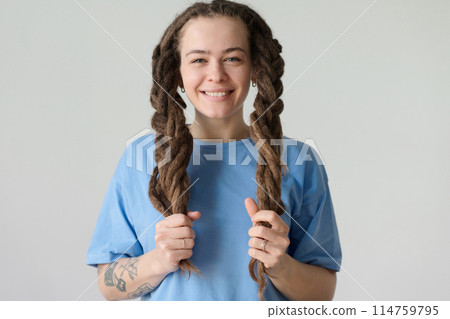 Minimal portrait of carefree Caucasian woman holding long dreadlocks in braids and smiling at camera copy space 114759795