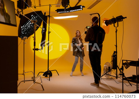 Videographer capturing footage in a yellow room with a camera Videographer capturing footage in a yellow room with a camera 114760073