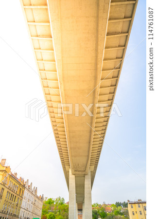 The expansive underbelly of the Nusle Bridge stretches above, showcasing the engineering against a clear sky in Prague, Czechia 114761087