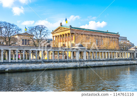 A serene view of the Old National Gallery located along the riverbank in Berlin, with classical architecture and clear skies. Germany 114761110