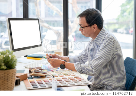 An experienced Asian male interior designer or architect is working on his project in the office. 114762712