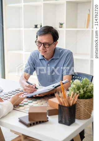 A male interior designer or architect is having a meeting with his client in the office. 114762720