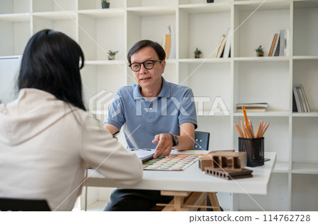A client is having a meeting to sign a building insurance contract paper in front of the contractor. A client is having a meeting to sign a building insurance contract paper in front of the contractor. 114762728