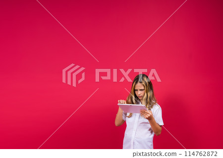 Online school app. Schoolgirl showing tablet computer Empty Screen Over red Background. Studio Shot 114762872