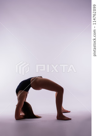 Young beautiful yoga female posing on a studio background 114762899
