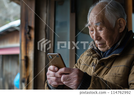 一位老人一臉困惑地操作智慧型手機 114762992