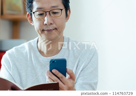 中年男子檢查他的智慧型手機和筆記本 114763729