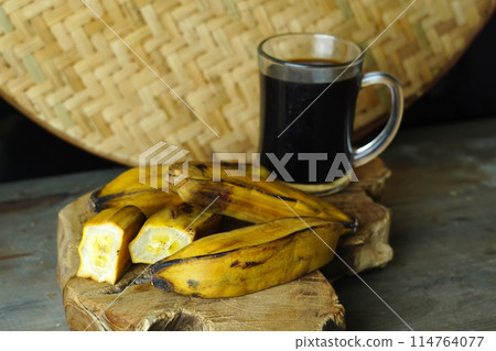 a halved steamed banana and a whole banana on a wooden cutting board a halved steamed banana and a whole banana on a wooden cutting board 114764077