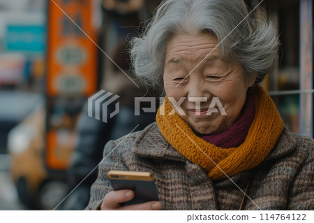 Senior woman smiling while looking at her smartphone Senior woman smiling while looking at her smartphone 114764122