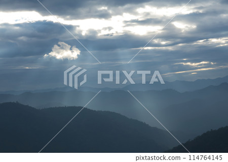 Sun rays filter through the clouds in hills of the valley illuminated by the sun's rays filtering through the clouds 114764145