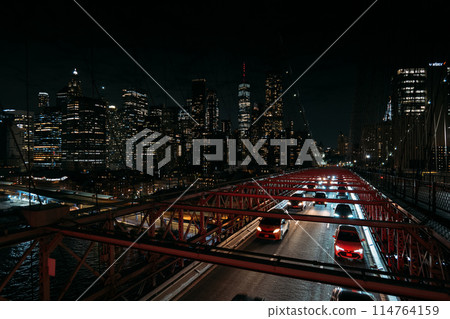 Night view of New York City skyline and busy traffic on illuminated bridge 114764159