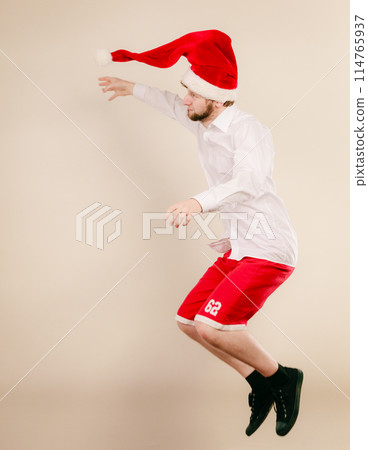 Active man in santa hat dancing and jumping. Active man in santa hat dancing and jumping. 114765937