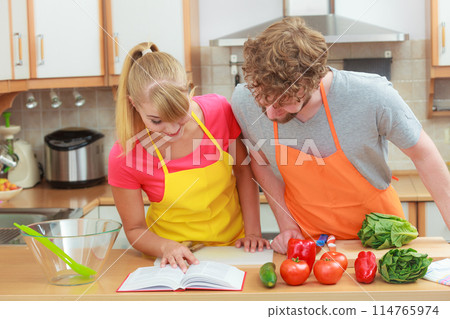 Couple cooking in kitchen reading cookbook Couple cooking in kitchen reading cookbook 114765974