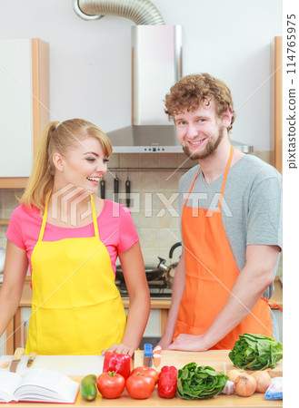 Couple cooking in kitchen reading cookbook 114765975