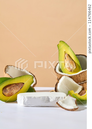 On the pastel background, an empty stone podium decorated with a lot of avocado halves and pieces of coconut. Delicious healthy fruit background On the pastel background, an empty stone podium decorated with a lot of avocado halves and pieces of coconut. Delicious healthy fruit background 114766462