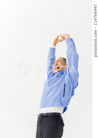 Man in work clothes stretching vertical Man in work clothes stretching vertical 114766947