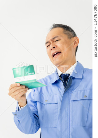 穿著工作服的男人哀嘆銀行存摺垂直 114767090
