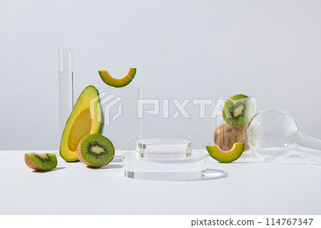 Two podiums in round shaped stacked on each other, displayed with few slices of avocado and kiwi. Concept laboratory tests and research natural extract making cosmetics 114767347