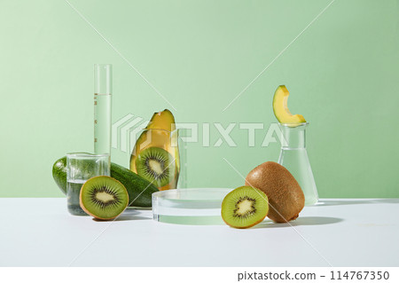 Laboratory concept with different types of glassware arranged with kiwi and avocado cut in halves. Round podium with vacant space for beauty products presentation Laboratory concept with different types of glassware arranged with kiwi and avocado cut in halves. Round podium with vacant space for beauty products presentation 114767350
