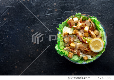 Caesar salad with chicken breast, lettuce, croutons, and a lemon Caesar salad with chicken breast, lettuce, croutons, and a lemon 114769920