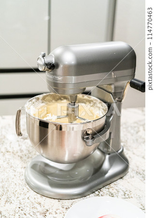 Stand mixer whips up creamy buttercream frosting to perfection, ready for dessert decorating. 114770463