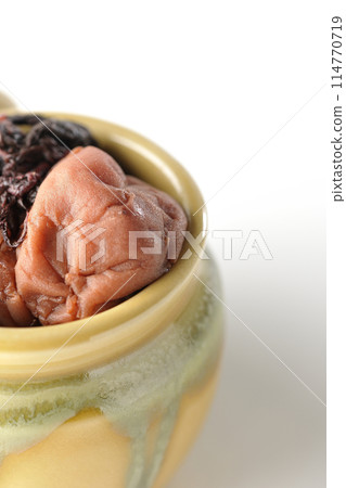 Pickled plums and red shiso in a jar photographed on a white background Pickled plums and red shiso in a jar photographed on a white background 114770719