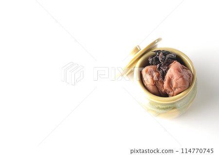 Aerial view of pickled plums and red shiso in a jar on a white background Aerial view of pickled plums and red shiso in a jar on a white background 114770745