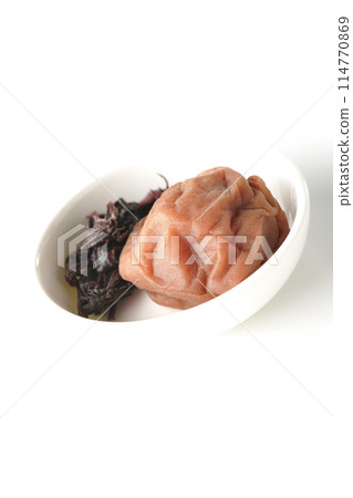 Red shiso and pickled plums served on a small white round plate photographed on a white background Red shiso and pickled plums served on a small white round plate photographed on a white background 114770869