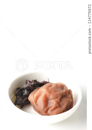 Red shiso and pickled plums served on a small white round plate photographed on a white background Red shiso and pickled plums served on a small white round plate photographed on a white background 114770872