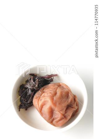 Aerial view of red shiso and pickled plums served on a small white round plate on a white background 114770935