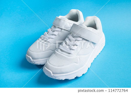 white kid sneakers with velcro on blue background. High quality photo 114772764