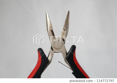 A pair of pliers with a red handle and a black handle A pair of pliers with a red handle and a black handle 114772797