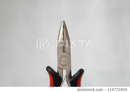 A pair of pliers with a silver head and black handles 114772804