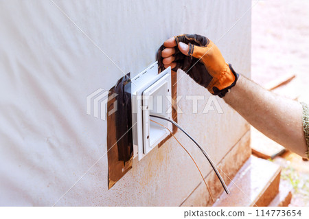 Electrical box is mounted on external wall in deep plastic box that is weatherproof Electrical box is mounted on external wall in deep plastic box that is weatherproof 114773654